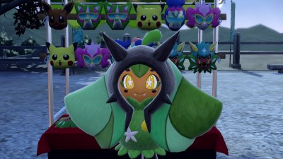 A Pokémon Scarlet and Violet: The Teal Mask screenshot of Ogerpon in front of a mask stand at the festival.
