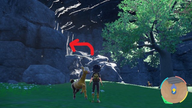 A Pokemon Scarlet and Violet screenshot of Area Zero. A red arrow points in the direction of a rock formation to the left of a large tree.