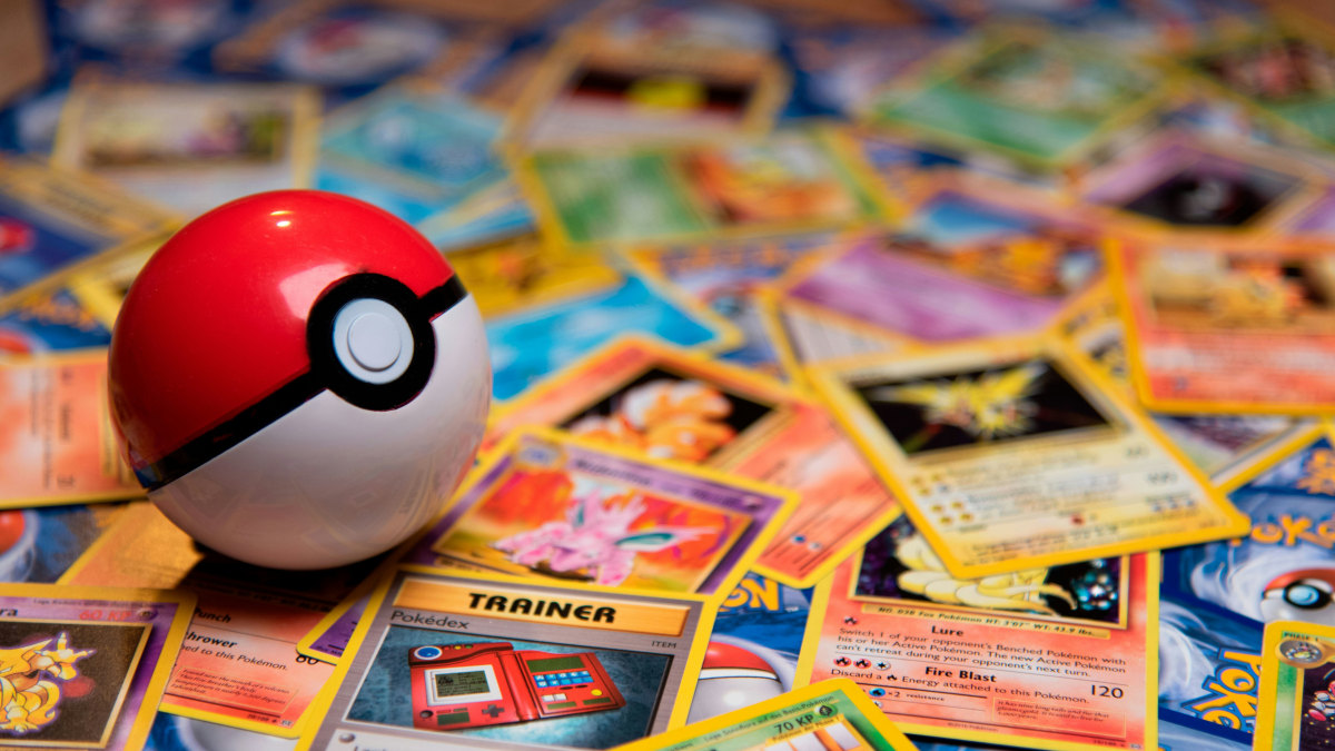 A photograph of a Poke Ball toy on top of many different classic Pokemon cards.